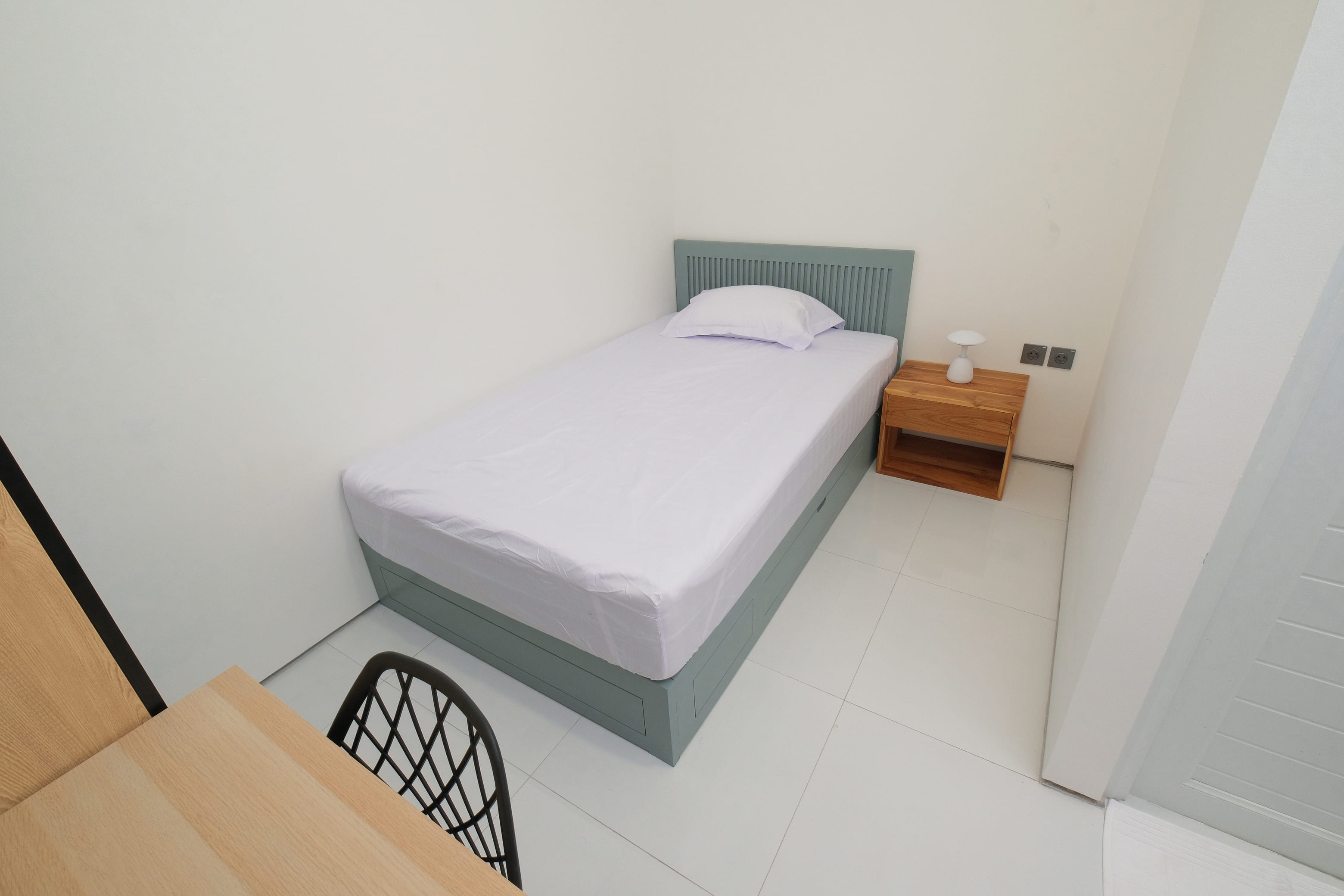 Tempat tidur single dengan headboard dan nakas kayu