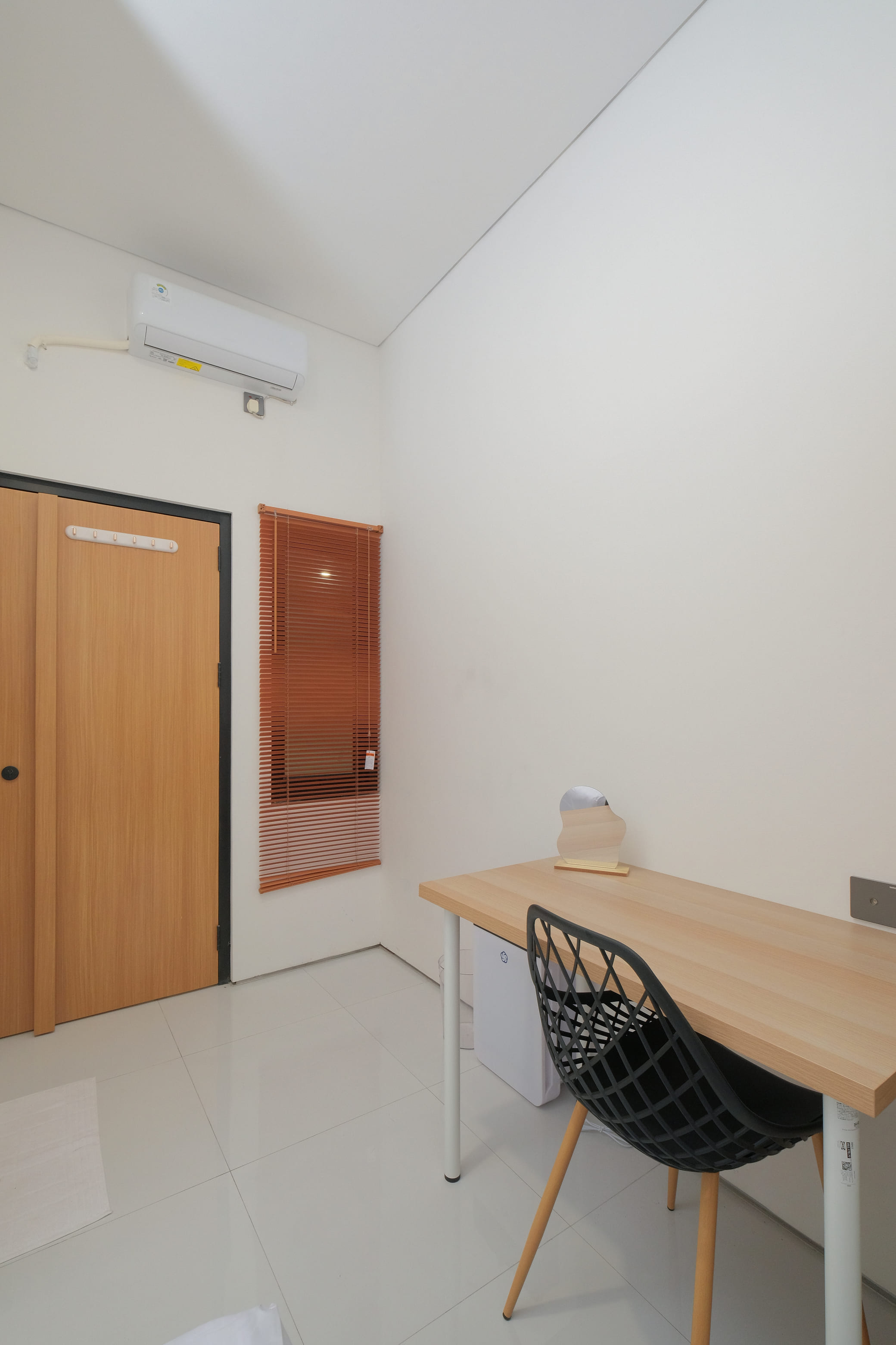 Interior kamar dengan AC, pintu kayu, meja, dan blinds