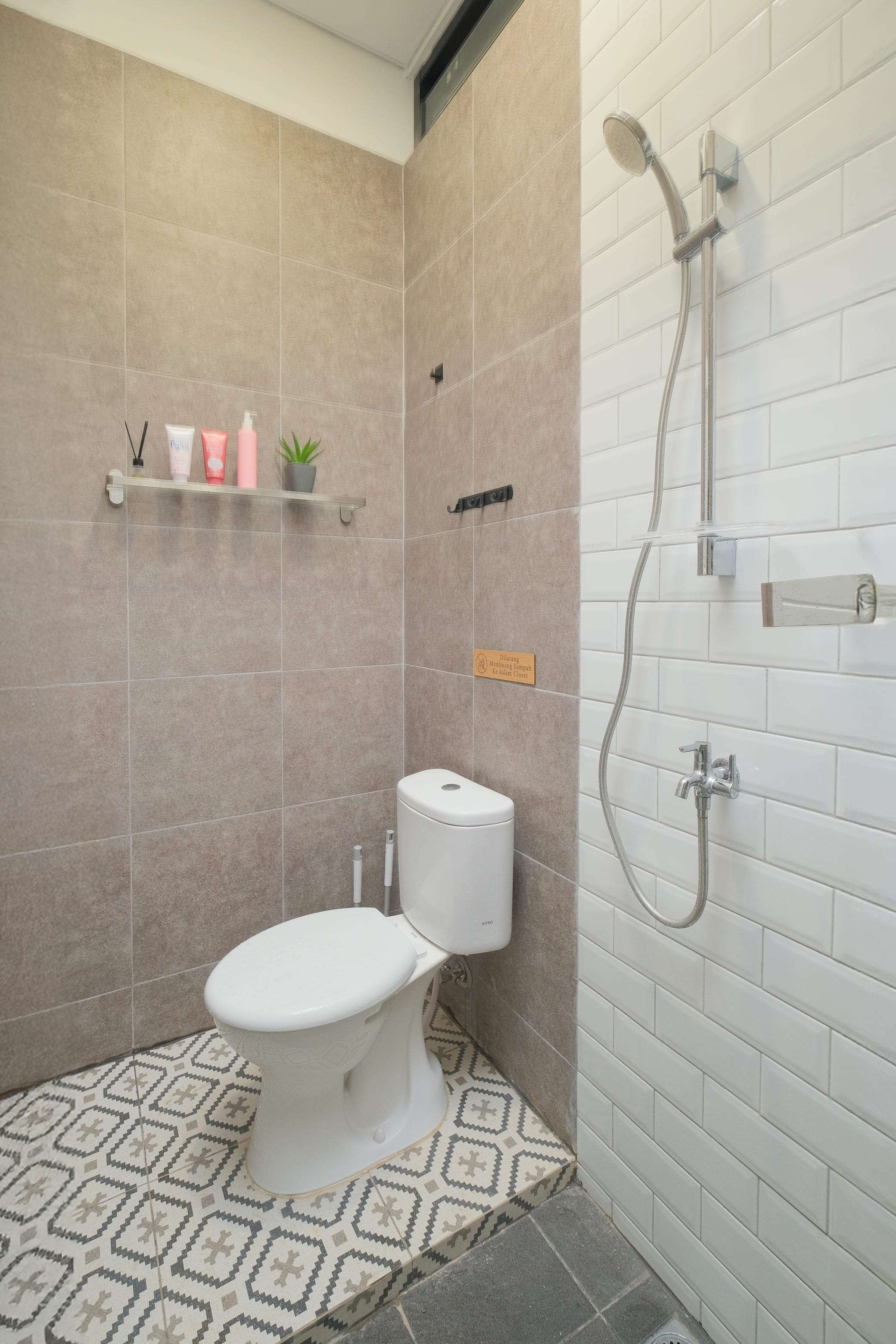 Kamar mandi privat dengan shower, toilet, dan rak perlengkapan
